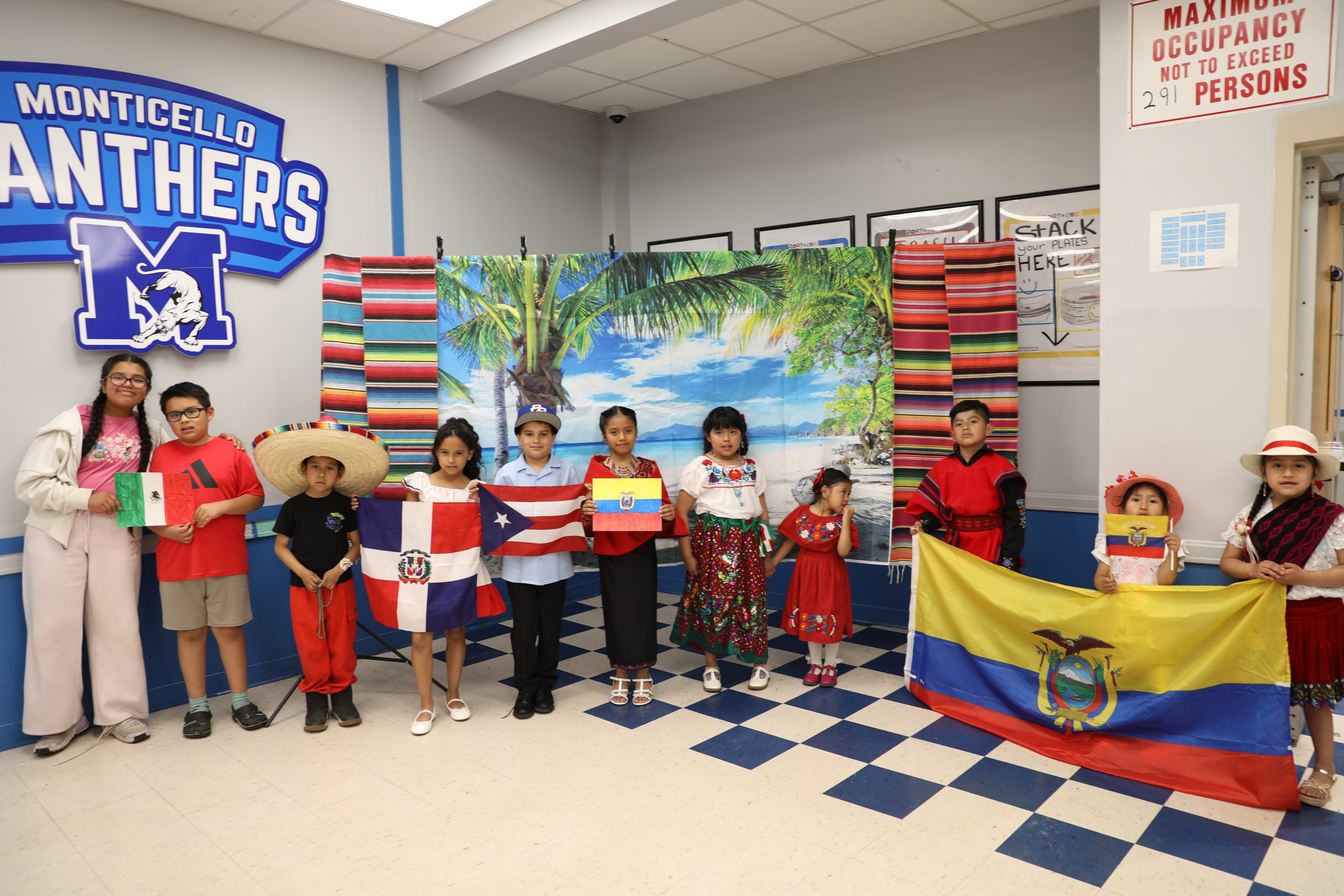 a group of children holding flags from their home countries and wearing traditional clothing pose