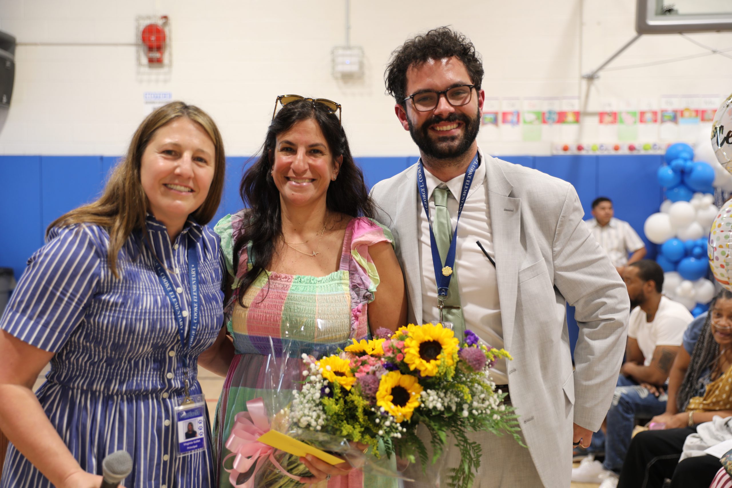 THe principals are posing with a PTO member who they gave a bouquet of flowers to 
