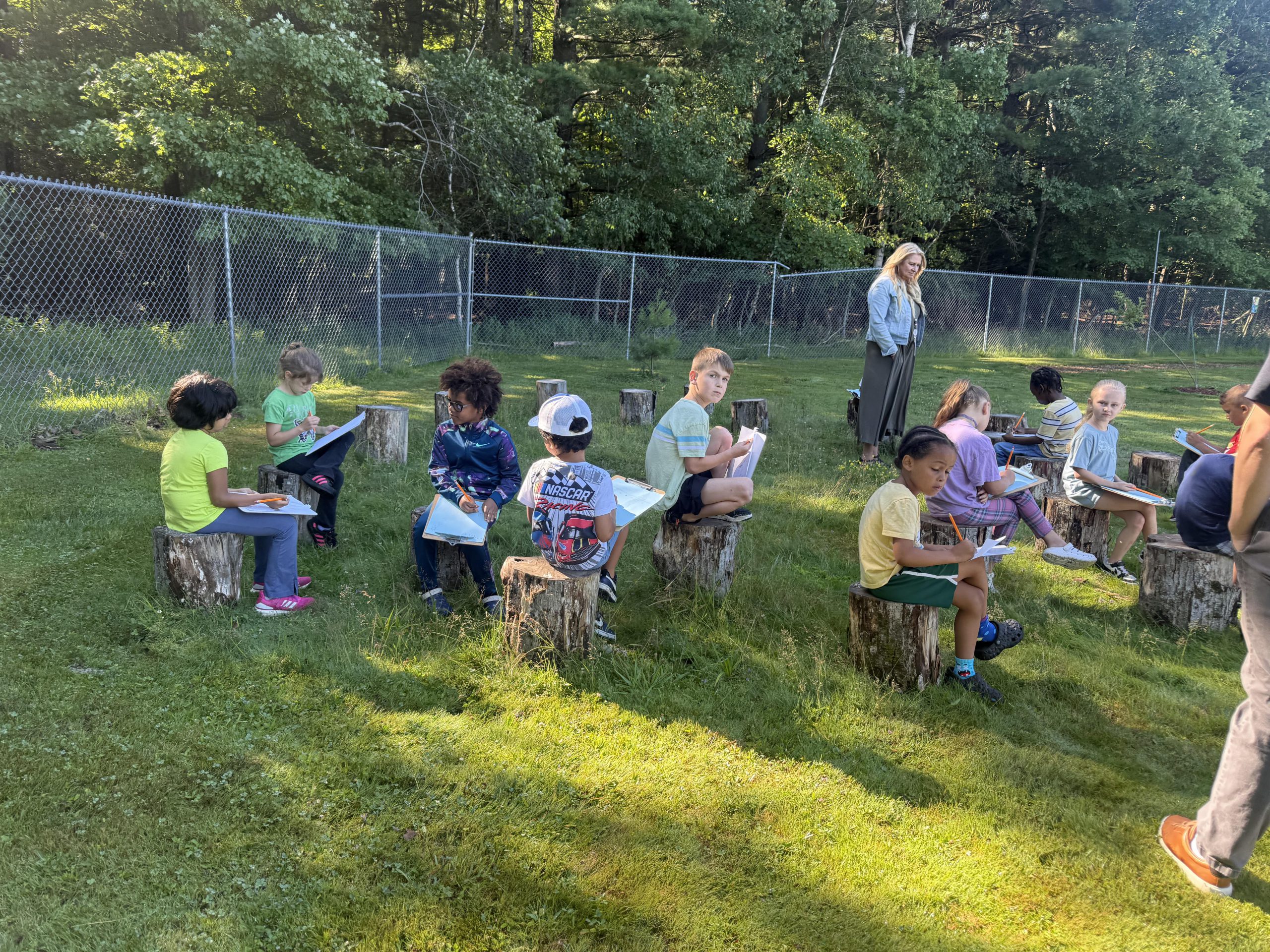 a group of students are seated outdoors engaged in reading