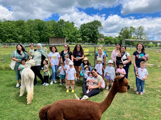 the families who participated in the field trip to Buck Brook Farm pose with a llama