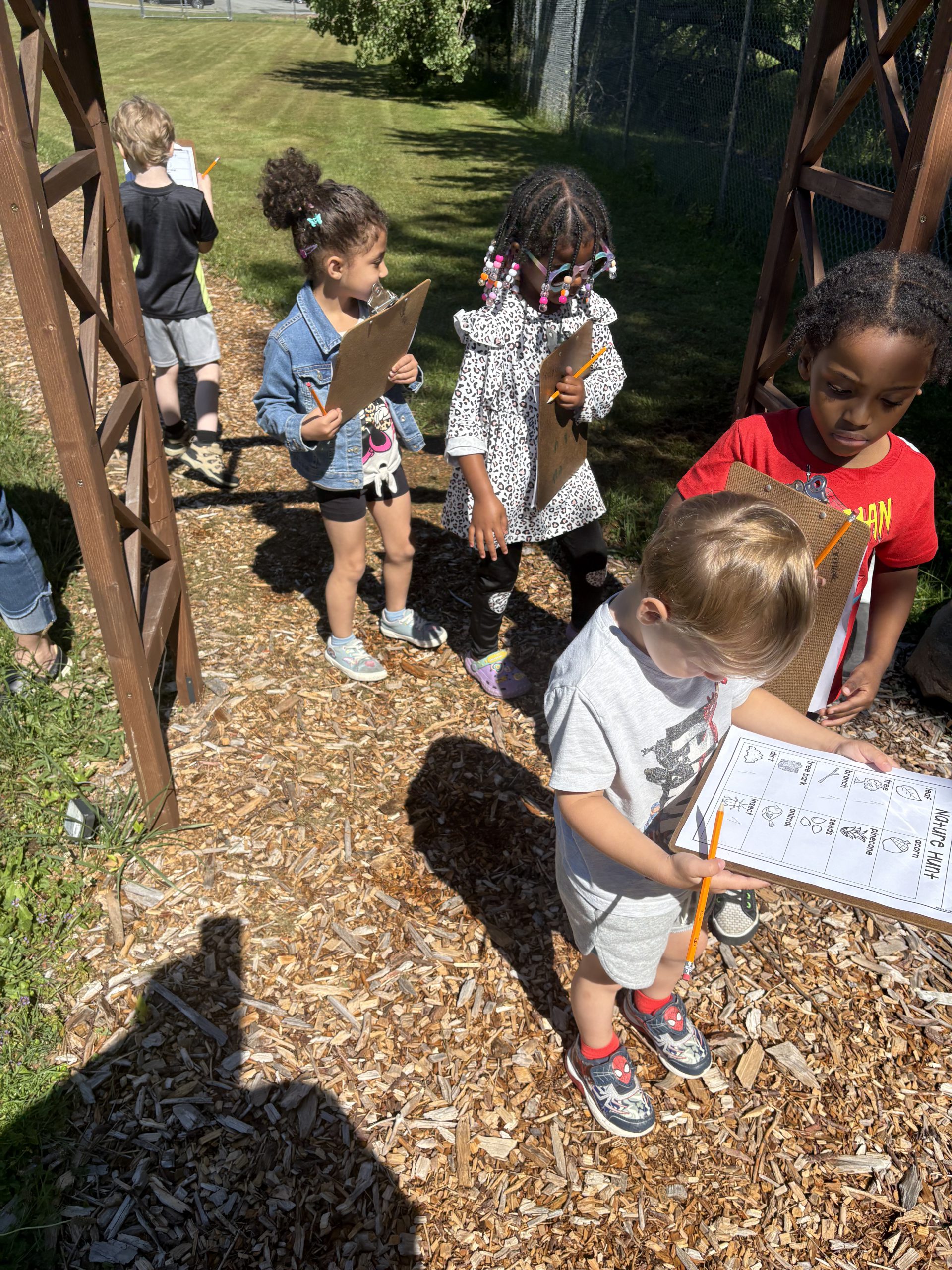 a group of students walk on the nature trail holding scavenger hunt instructions
