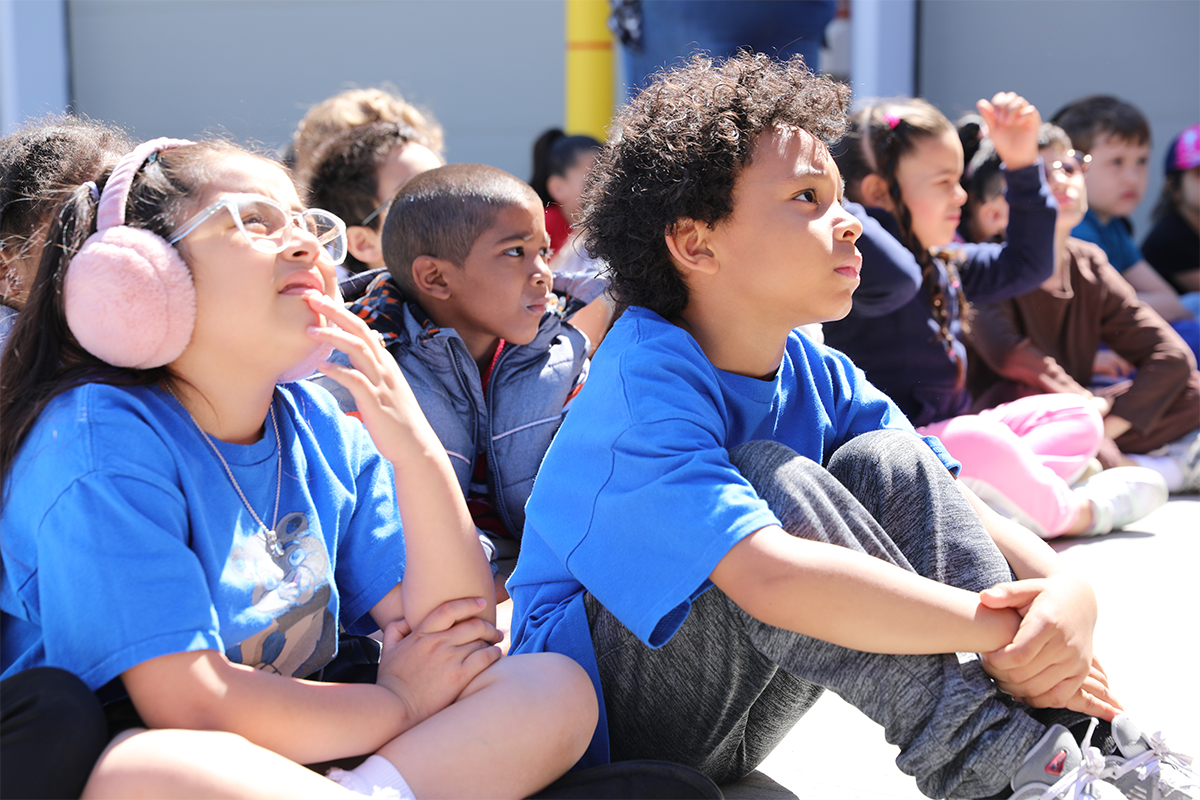 Elementary School students intently watch an outdoor presentation