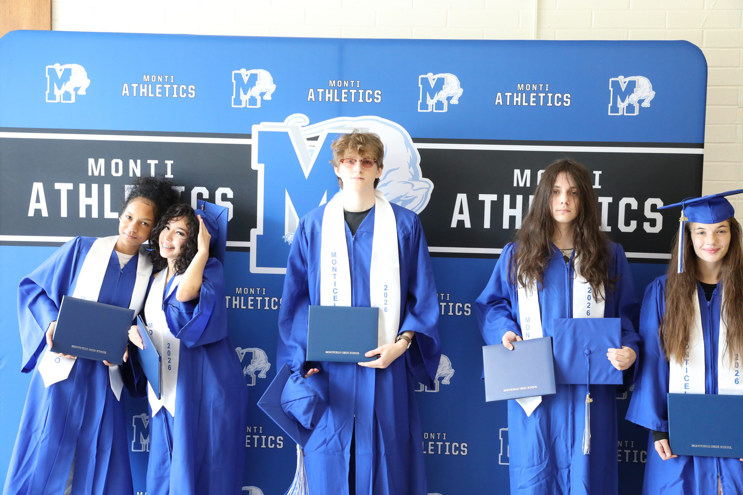 a group of graduates pose behind a backdrop