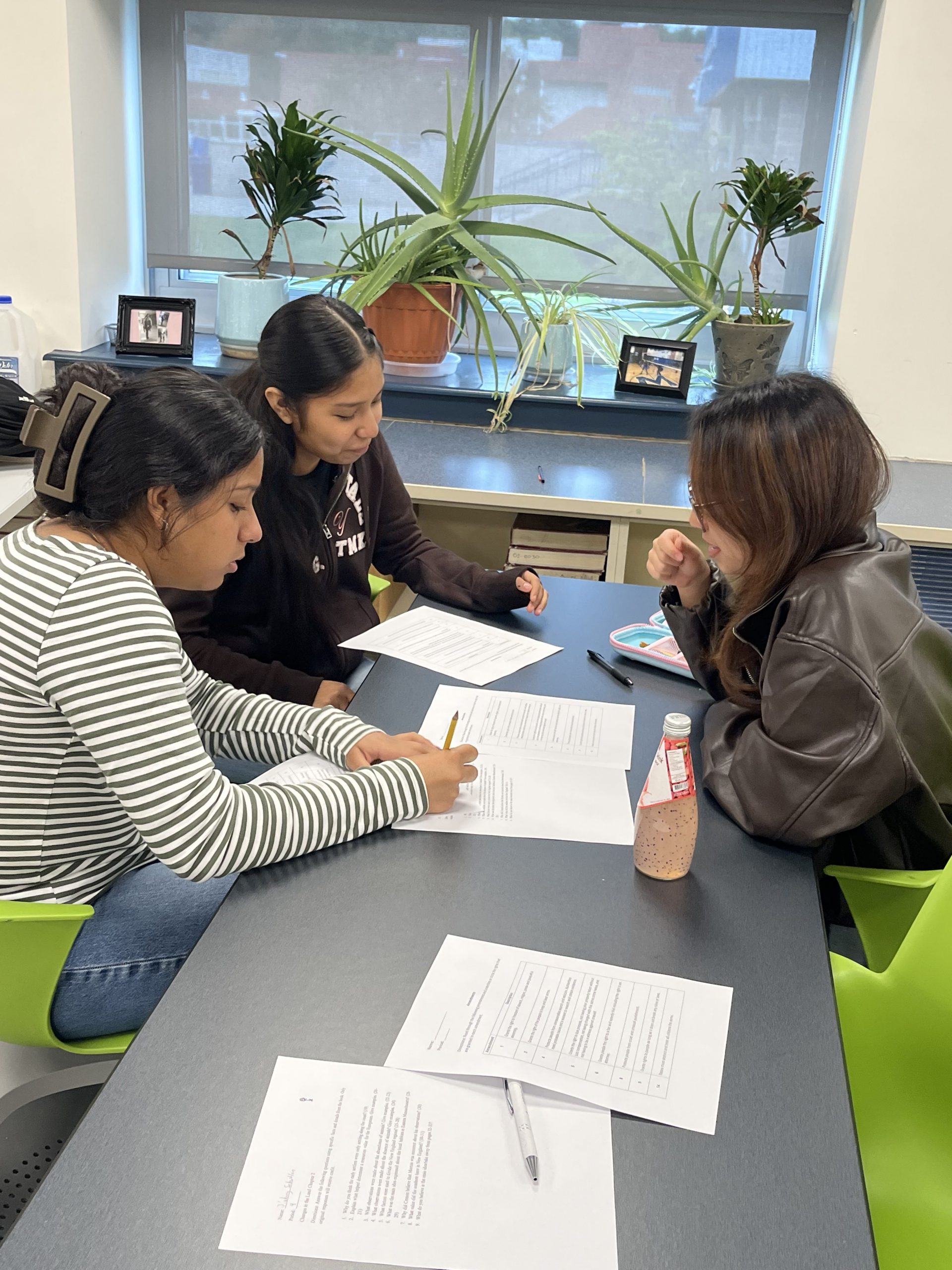 three students work on an assignment collaboratively at a table