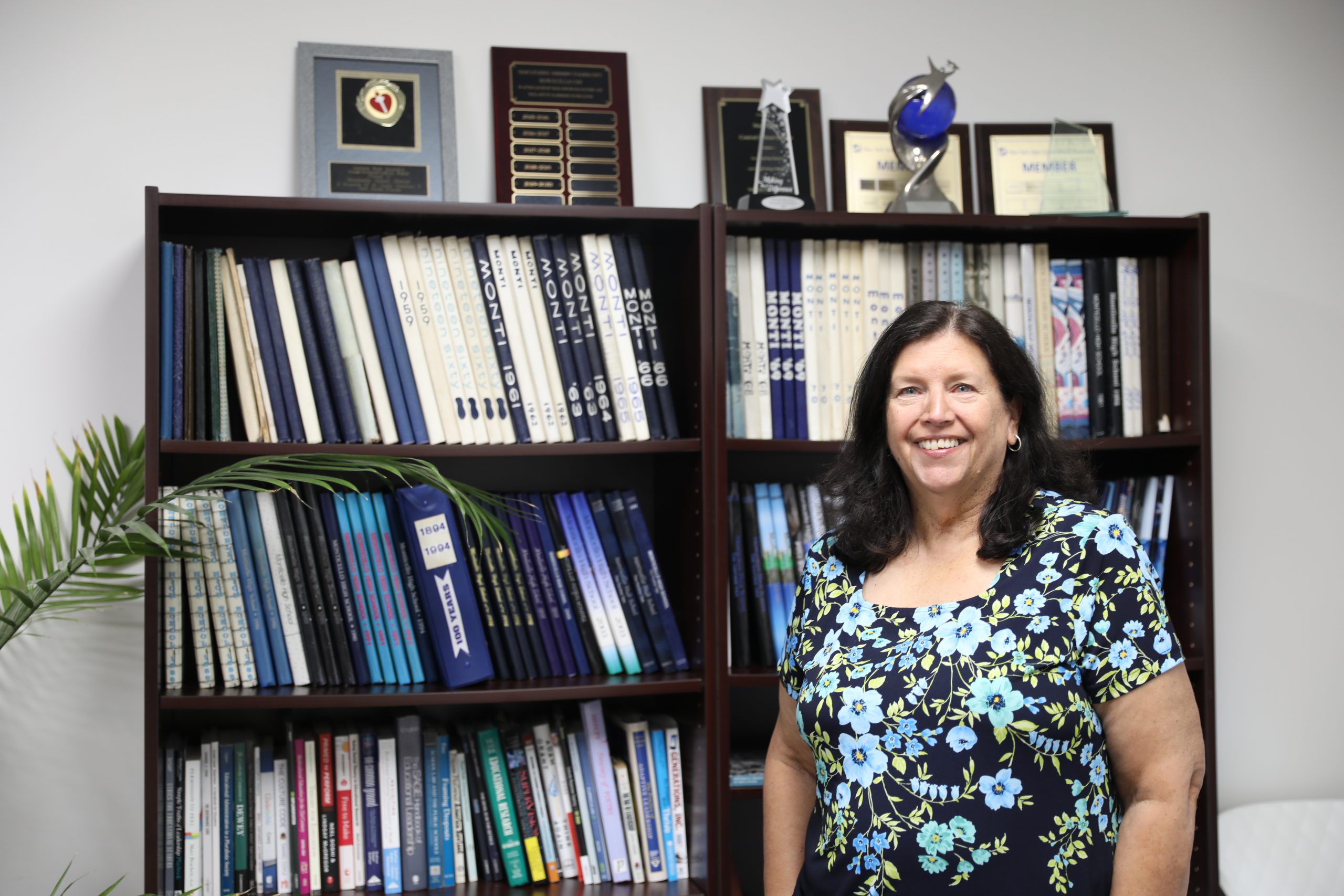 Assistant Superintendent Failla, who received an Excellence in Administration award poses next to a bookshelf.