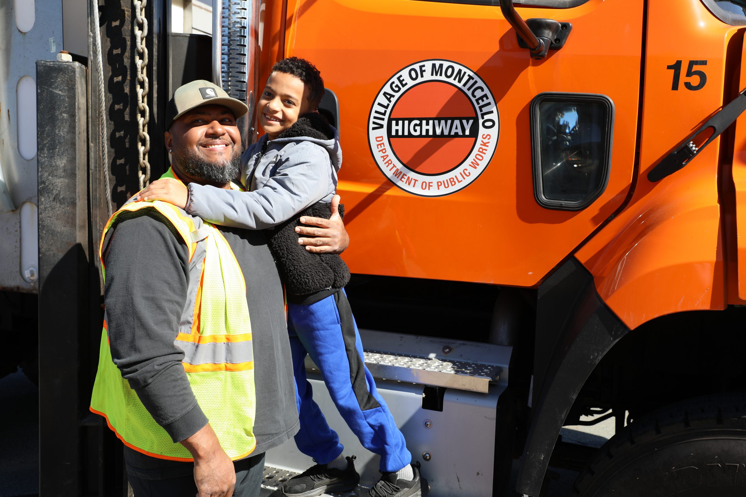 a student poses with a worker from the highway department during touch a truck day